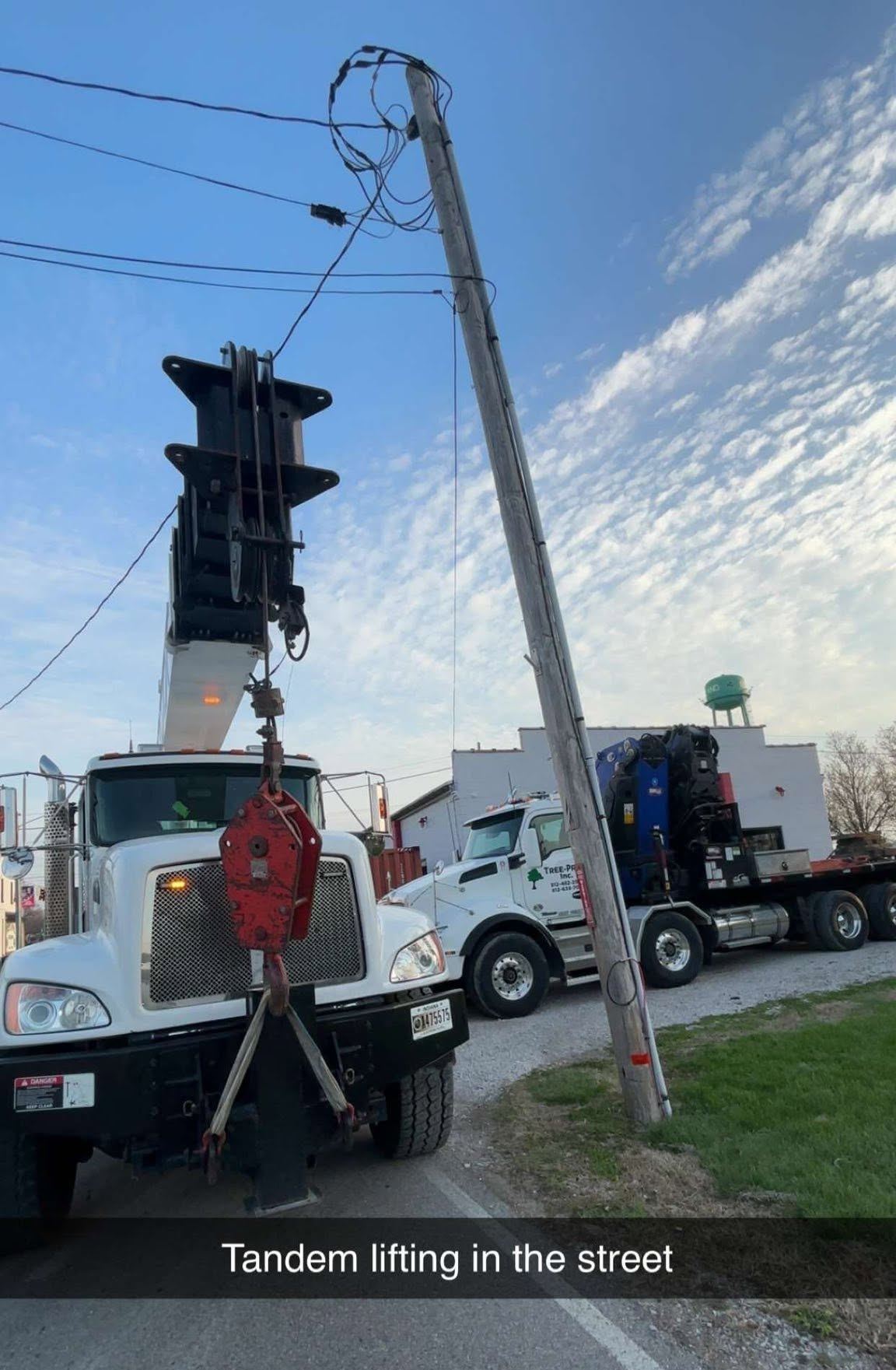 Two boom trucks lifting a heavy trunk section together
