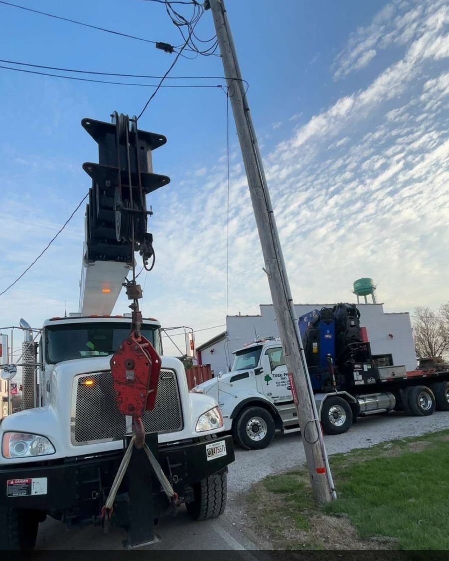 Two boom trucks lifting a heavy trunk section in tandem