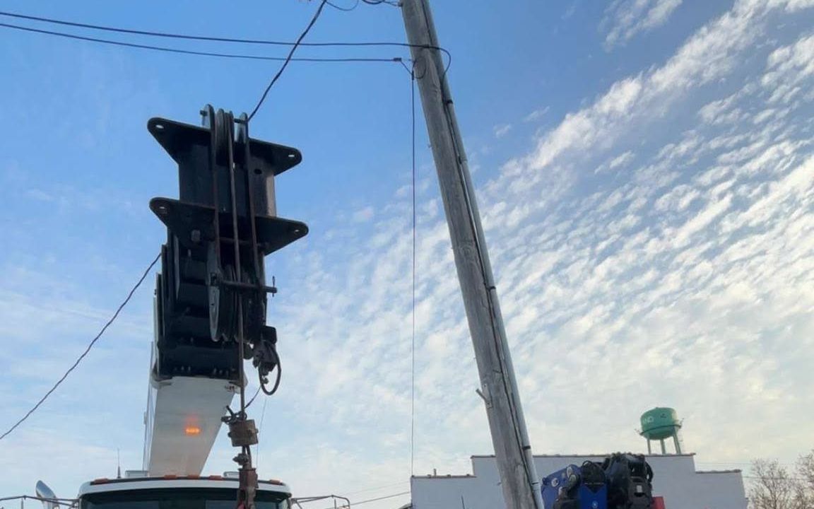 Two boom trucks performing a tandem lift in the street